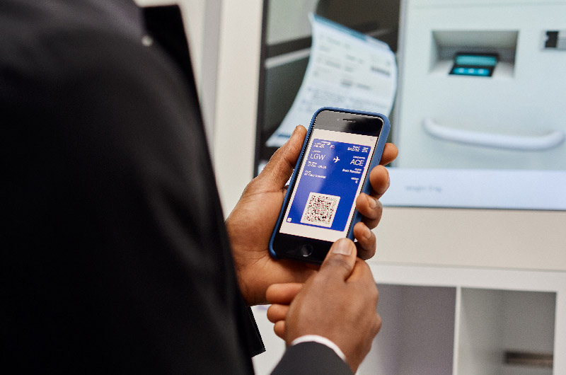 Passenger using digital boarding pass on their phone to drop bags using self-service terminal